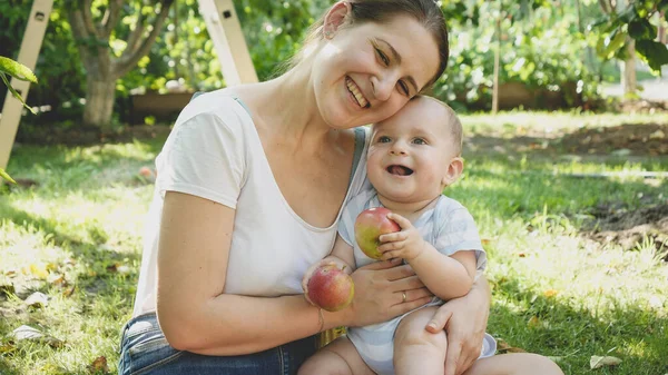 Jeune mère étreignant son fils bébé aeting pommes mûres cueillies dans la maison jardin arrière-cour. Concept de développement de l'enfant, parentalité et alimentation biologique saine. — Photo