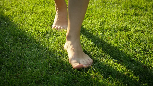 Close-up de mulher descalça andando no gramado de grama verde fresco. — Fotografia de Stock