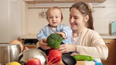Mutfakta sebze ve çatal bıçaklarla oynayan küçük oğluyla mutlu bir anne. Küçük şef kavramı, çocukların yemek pişirmesi, birlikte iyi bir aile zamanı.