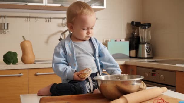 台所でパンを調理しながら、面白い小さな赤ちゃんの男の子はボウルに小麦粉で遊んで.小さなシェフ、子供たち料理、健康的な栄養の概念. — ストック動画