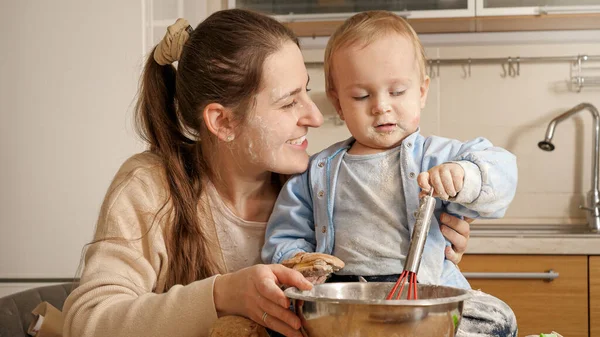 Malý chlapec pomáhá své matce dělat těsto a péct chleba v kuchyni. Koncept malého šéfkuchaře, děti vařící jídlo, zdravá výživa. — Stock fotografie
