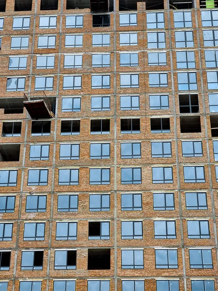 Facade of high modern building under construction with partly installed windows in frames — Stock Photo, Image