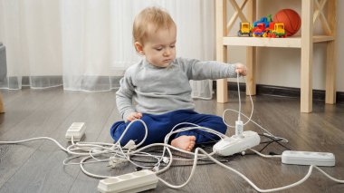 Küçük bebek yalnız kaldı. Elektrik kabloları ve kablolarıyla oynuyor.