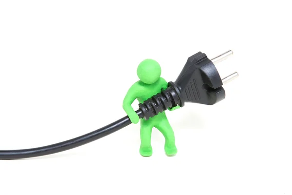 Pequeno fantoche de plasticina verde mantém um plugue elétrico — Fotografia de Stock