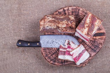 Küçük bir alan derinliği. Üzerine baharatlar serpiştirilmiş domuz yağı tabakası. Soğan kafanın yanında. Mutfak bıçağı.