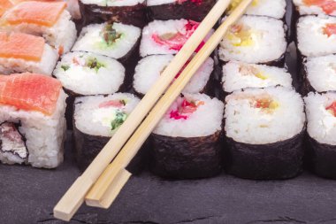 Beyaz bir arka planda. Üzerindeki siyah taş deniz ürünleri, suşi parçaları. Yakın plan. Asya yemekleri.