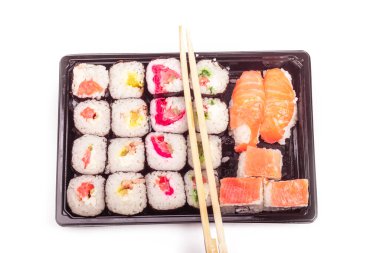 Beyaz bir arka planda. Üzerinde siyah plastik deniz ürünleri, suşi parçaları var. Yakın plan. Asya yemekleri.