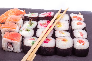 Beyaz bir arka planda. Üzerindeki siyah taş deniz ürünleri, suşi parçaları. Yakın plan. Asya yemekleri.