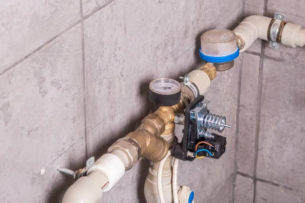 瓷砖墙上有一根有水的管子 还安装了一个水表 自动化连接以确保系统的安全和保持所需的压力 — 图库照片