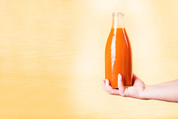 Kuning Latar Belakang Kayu Botol Kaca Dengan Cairan Oranye Dalamnya — Stok Foto