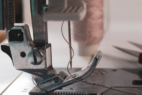 Швейная машинка. фут и игла с ниткой в центре внимания. крупным планом. есть легкая тонировка рамы.