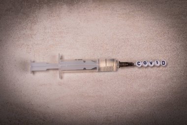 Hastalığa karşı enjeksiyonlu bir şırınga. Şırınganın üzerinde yazılı çocuk oyuncağı mektupları var. yakın plan.