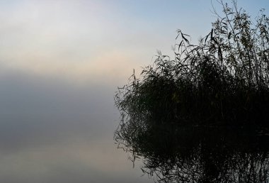 Sabahın erken saatlerinde sisli göl ve güneş doğarken