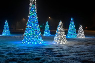 Halk aydınlatılmış Noel süslemeleri karın üzerinde duruyor