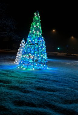 Halk aydınlatılmış Noel süslemeleri karın üzerinde duruyor