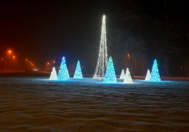 Halk aydınlatılmış Noel süslemeleri karın üzerinde duruyor