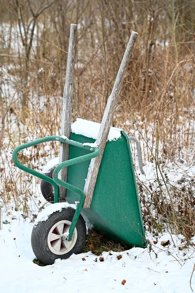Big green wheelbarrow standing in snow in december — Zdjęcie stockowe