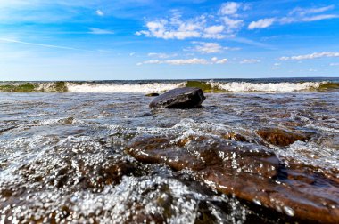 Sahildeki taşın üzerindeki dalgaların düşük perspektifi