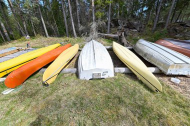 Boats kayaks and canoes lying on tree trunks