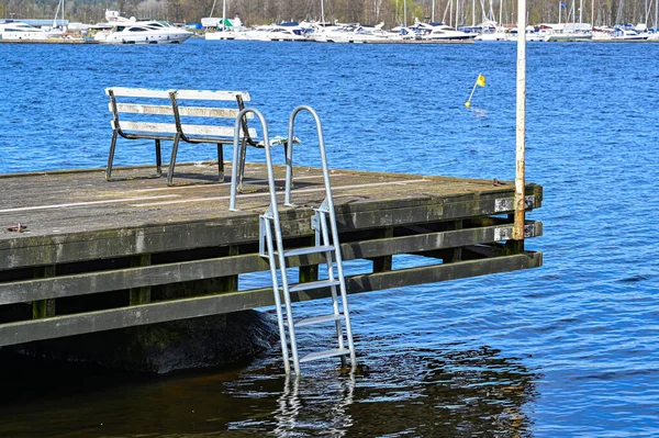 Bench and ladder on wooden jetty over lake in Sweden — Fotografia de Stock