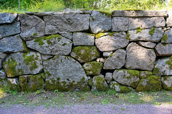 big old wall made of stones covered in moss Karlslund garden Orebro august 4 2022