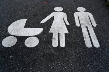 Bebek arabalı bir kadın ve sadece aile otoparkı için boyanmış bir adamla otopark.