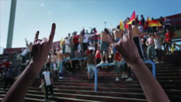 サッカースタジアムで悪魔の角の手のサインを示す女性の手 — ストック動画