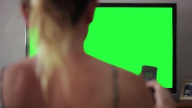 Oturma odasında Yeşil Ekranlı Kadın Televizyon İzliyor. Geriye bak. Yakın çekim. 4K Çözünürlüğü.