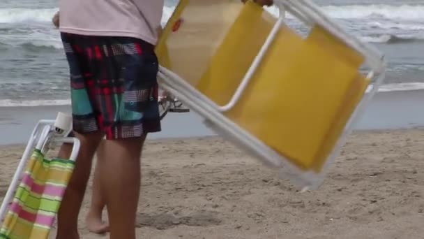 背景に海と折りたたみビーチチェアを持つ男性 — ストック動画