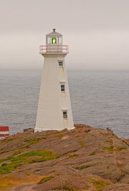 Lighthouse on a cloudy coast clipart