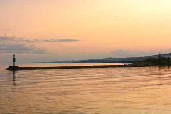 Des eaux calmes au coucher du soleil sur un brise-lames portuaire — Photo