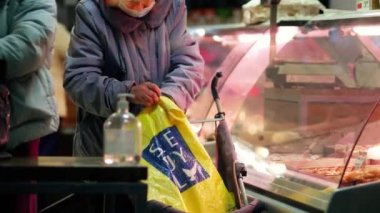 Yaşlı bir kadın bir mağazadan et alır. Bir emekli cam bir vitrinin önünde duruyor.