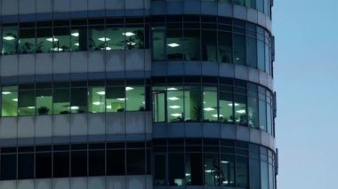 Günbatımı gökyüzüne karşı modern gökdelenli ofis binası. Işıklar açık.