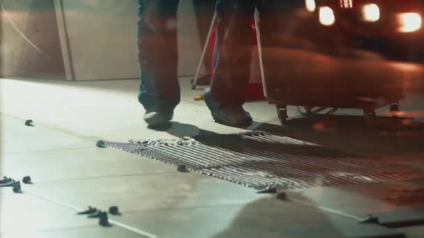 Los hombres con overoles esparcen cemento en el suelo para asegurar las baldosas. Trabajadores de la construcción — Vídeos de Stock