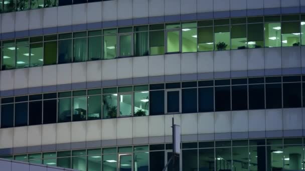 Moderno edificio de oficinas de gran altura en la noche contra el cielo del atardecer. Luces encendidas — Vídeos de Stock