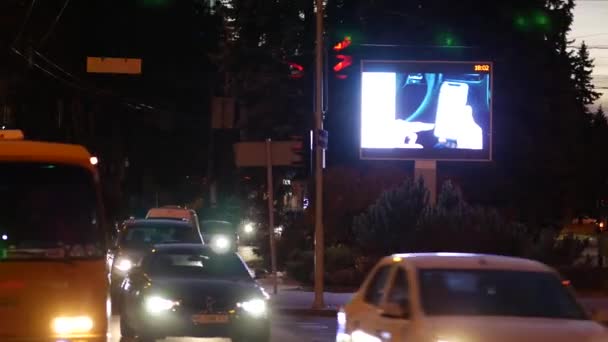 Hatalmas fényes LED képernyő videohirdetéssel közel közlekedési lámpák a sugárúton. — Stock videók