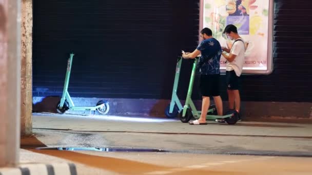 Los jóvenes activan el alquiler de scooters en la calle. Scooters eléctricos para compartir — Vídeo de stock