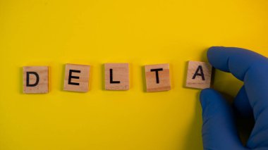 Delta 'nın yerine Omicron versiyonu. Koronavirüsün yeni tehlikeli bir türü olan COVID-19 Omicron ortaya çıktı. Mavi eldivenler hazır. Renkli sarı arkaplan üzerine kelime Delta