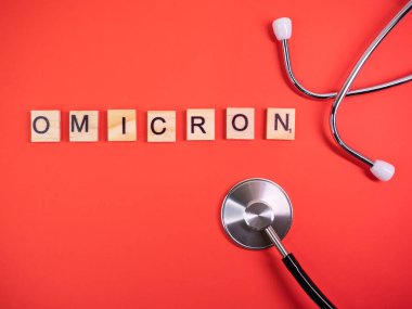 Delta 'nın yerine Omicron versiyonu. Koronavirüsün yeni tehlikeli bir türü olan COVID-19 Omicron ortaya çıktı. Phonendoskop. Renkli kırmızı arkaplanda omikron sözcükleri