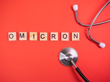 Delta 'nın yerine Omicron versiyonu. Koronavirüsün yeni tehlikeli bir türü olan COVID-19 Omicron ortaya çıktı. Phonendoskop. Renkli kırmızı arkaplanda omikron sözcükleri