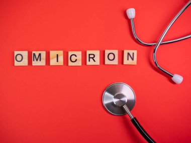 Delta 'nın yerine Omicron versiyonu. Koronavirüsün yeni tehlikeli bir türü olan COVID-19 Omicron ortaya çıktı. Phonendoskop. Renkli kırmızı arkaplanda omikron sözcükleri