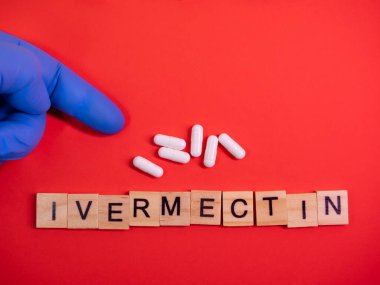 Renkli kırmızı kağıt doku arka planında Ivermectin. Parazit önleyici ilaçlar alıyorum. Kayıt dışı ilaç kullanımı onaylandı. Covid-19 terapisi. Eczane konsepti. Uzayı kopyala Tasarım şablonunu düzenle