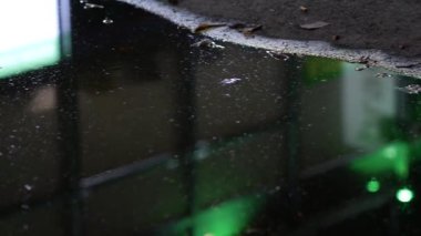 Yağmur damlaları gece birikintilerine düşer. Yüzey dalgalanmaları. Pencerelerin yansıması