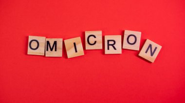 Omicron varyantı Delta 'nın yerini alır. Koronavirüsün yeni tehlikeli bir türü olan COVID-19 Omicron ortaya çıktı. Renkli kırmızı arkaplanda omikron sözcükleri