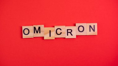 Omicron varyantı Delta 'nın yerini alır. Koronavirüsün yeni tehlikeli bir türü olan COVID-19 Omicron ortaya çıktı. Renkli kırmızı arkaplanda omikron sözcükleri