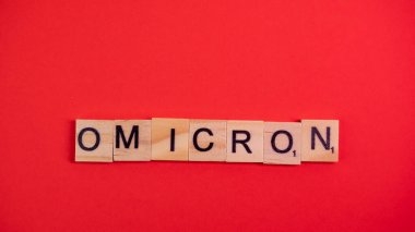 Omicron varyantı Delta 'nın yerini alır. Koronavirüsün yeni tehlikeli bir türü olan COVID-19 Omicron ortaya çıktı. Renkli kırmızı arkaplanda omikron sözcükleri