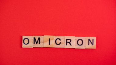 Omicron varyantı Delta 'nın yerini alır. Koronavirüsün yeni tehlikeli bir türü olan COVID-19 Omicron ortaya çıktı. Renkli kırmızı arkaplanda omikron sözcükleri