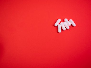 Kırmızı kağıt kaplamalı beyaz ilaç kapsülleri. Makro hap ilaçlarını kapat. Büyük ilaç firması. Kayıt dışı ilaç kullanımı onaylandı. Eczane konsepti. Uzayı kopyala Tasarım şablonunu düzenle.
