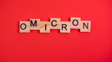 Omicron varyantı Delta 'nın yerini alır. Koronavirüsün yeni tehlikeli bir türü olan COVID-19 Omicron ortaya çıktı. Renkli kırmızı arkaplanda omikron sözcükleri