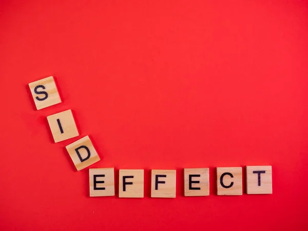 Words side effect on colored red paper texture background. Concept. Pill allergy. Concern of vaccine shot side effect or toxicity. Copy space. Mock up design.